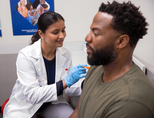 CVS pharmacist vaccinating male patient. 